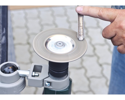 Drehender Schleifstein mit Stechbeitel und Hand zur Bearbeitung