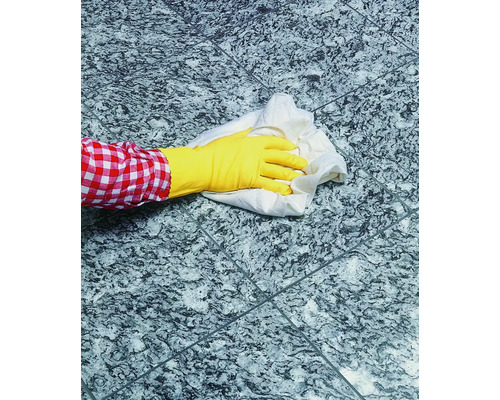 Person mit Gummihandschuh und Putzlappen reinigt Fliesenboden