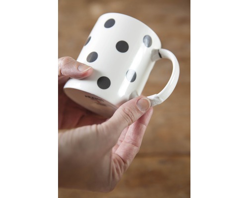 Keramiktasse mit Punktmuster in der Hand