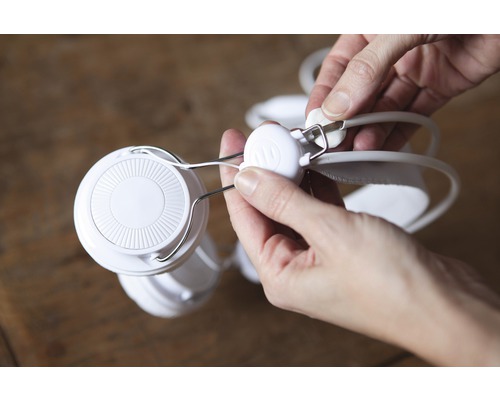 Weiße Kopfhörer werden von einer Person eingestellt.