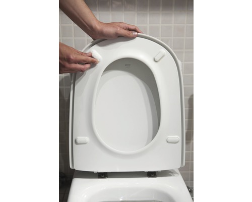 Montage eines Toilettensitzes auf einer Toilette.