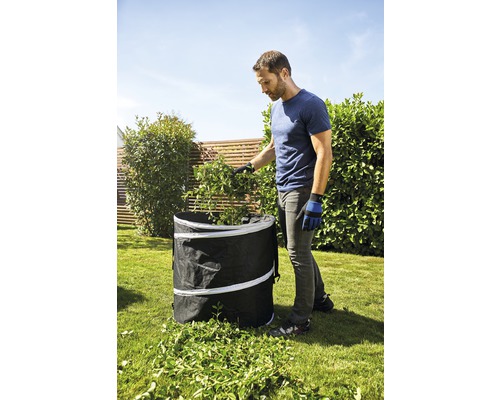 Mann befüllt einen Gartensack mit Gartenabfällen im Garten.