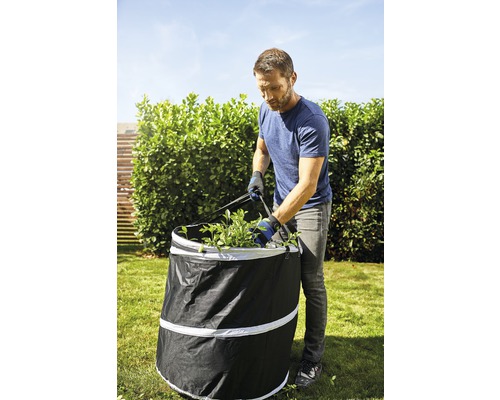 Gartenhelfer: Mann befüllt Laubsack mit Gartenschnitt im Garten.