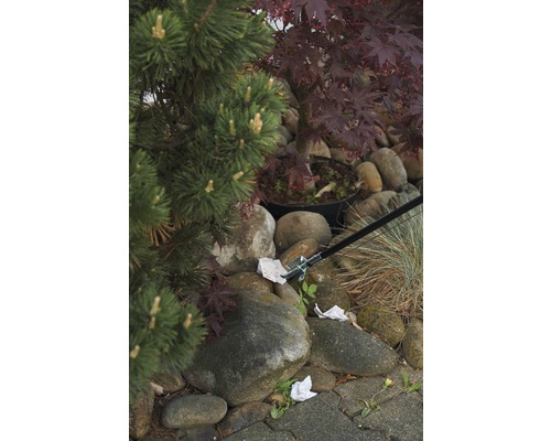 Garten mit Steinen, Pflanzen und Greifzange zum Aufsammeln von Müll