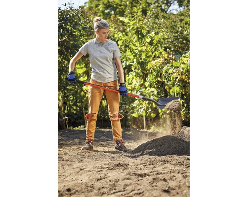 Eine Frau schaufelt Erde mit einem Spaten in einem Garten.