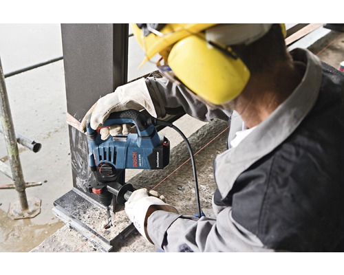 Ein Arbeiter bohrt mit einer Bosch GBH 3-28 F Professional Bohrmaschine ein Loch in einen Metallträger.