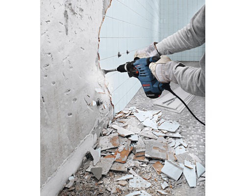 Eine Person entfernt Fliesen mit einem Bohrhammer von Bosch.