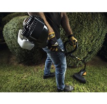Mann mit Motorsense beim Grasschneiden im Garten