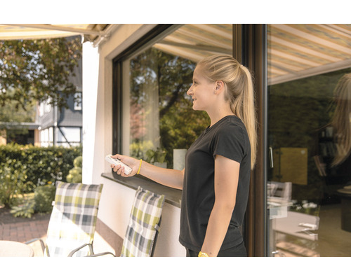 Frau bedient Markise mit Fernbedienung auf einer Terrasse