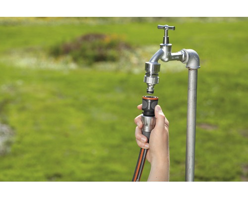 Gartenwasserhahn mit Schlauchanschluss und Gartenschlauch wird verbunden