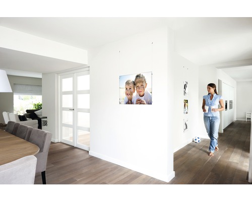 Helles Interieur mit Essbereich, Durchgang und einer Frau, die an einer Fotoaufhängung mit Kinderbild vorbeigeht