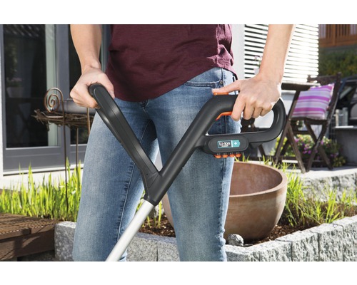 Person bedient einen Akku-Rasentrimmer im Garten.