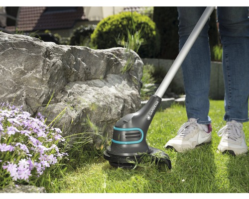 Person benutzt einen Gardena Akku-Rasentrimmer im Garten.