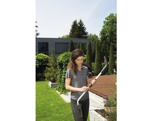 Frau hält eine Akku-Grasschere im Garten.