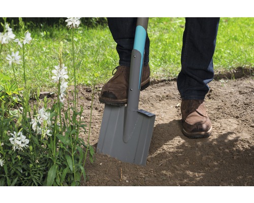 Eine Person benutzt einen Spaten im Garten, umzugraben.