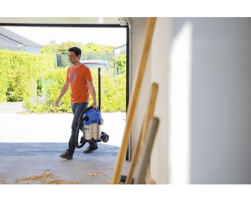 Ein Mann trägt einen Nass Trockensauger in einer Garage.
