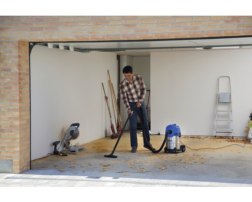 Mann saugt Garage mit Mehrzwecksauger