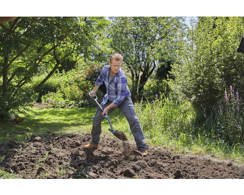 Mann gräbt mit einem Spaten im Garten um