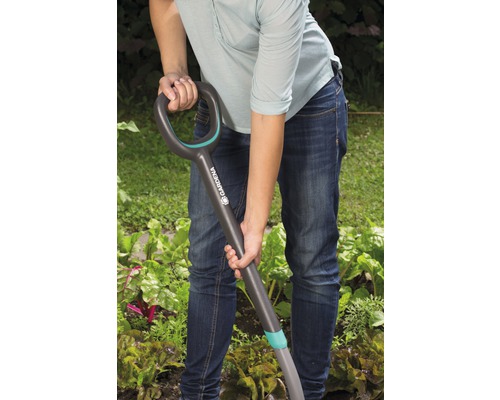 Eine Person benutzt einen Spaten im Garten.
