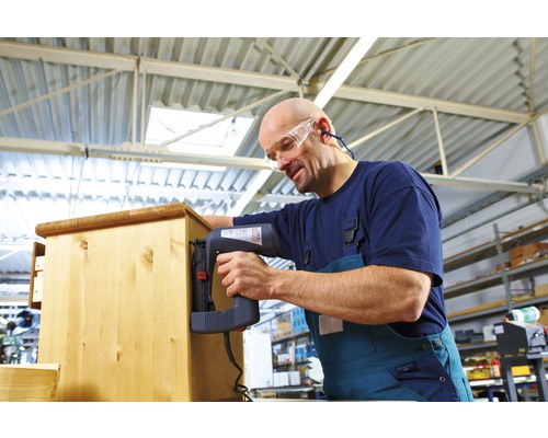 Handwerker befestigt Holz mit einem Elektrotacker