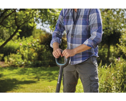 Eine Person hält einen Spaten der Marke Gardena in einem Garten.