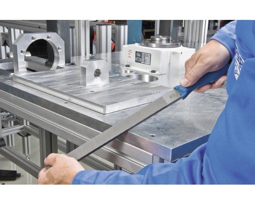 Eine Werkstatt-Szene zeigt eine Hand, die eine Werkstattfeile an einem Metallwerkstück verwendet.