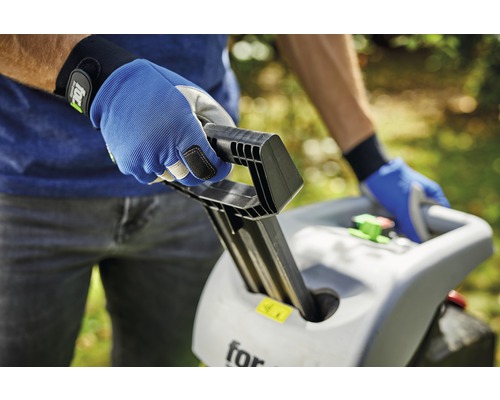 Eine Person bedient einen Gartenhäcksler mit Arbeitshandschuhen.
