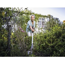 Frau benutzt eine Wurzelzange im Garten, um Unkraut zu entfernen