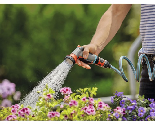 Eine Person bewässert mit einer Gardena Gartenspritze Blumen.