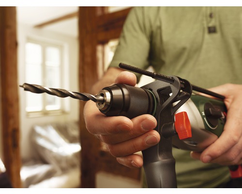 Mann hält eine Bohrmaschine mit Holzbohrer