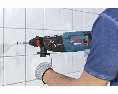 Eine Person bohrt mit einem Bohrhammer ein Loch in eine geflieste Wand