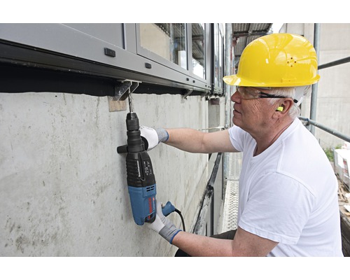 Handwerker bohrt mit einem Bohrhammer ein Loch in eine Betonwand