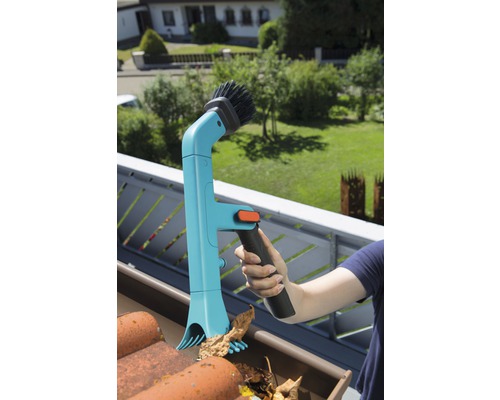 Person reinigt Dachrinne mit Dachrinnenreiniger