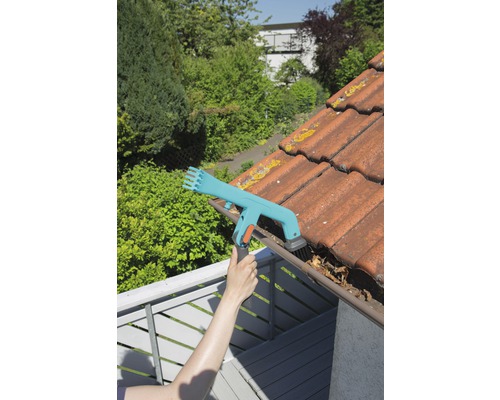 Person reinigt Dachrinne mit Dachrinnenreiniger