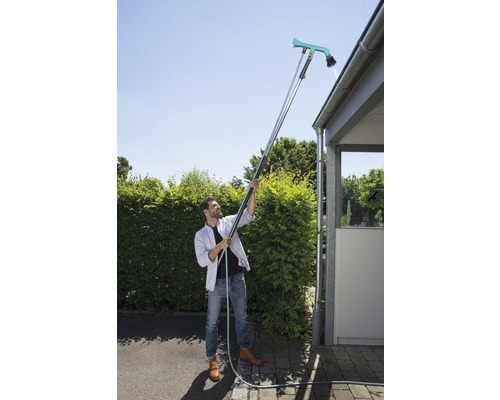 Mann reinigt Dachrinne mit Dachrinnenreiniger und Teleskopstiel.