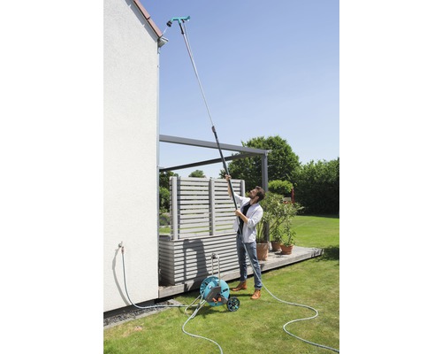 Mann reinigt Dachrinne mit Dachrinnenreiniger an Teleskopstiel