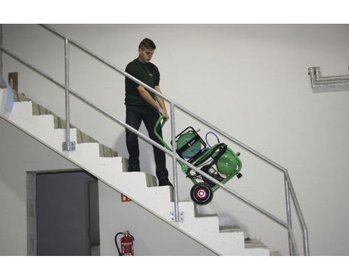 Eine Person transportiert einen mobilen Kompressor auf einer Treppe.