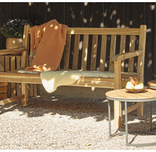 Gartenszene mit einer Holzbank, einer Wolldecke, einem Schaffell und einem Beistelltisch mit Obstschale
