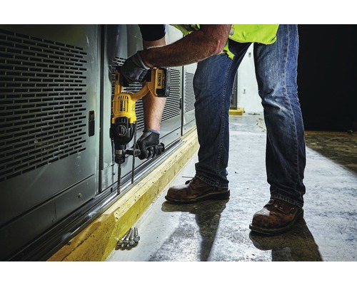 Ein Mann bohrt mit einer Bohrmaschine Löcher in eine Wand.