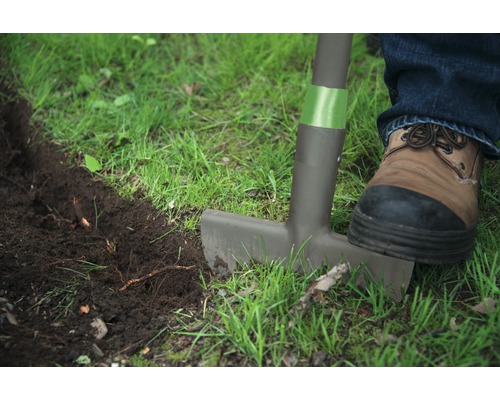 Gartenarbeit mit einem Rasenkantenstecher, ein Fuss mit Schuh auf dem Rasenkantenstecher