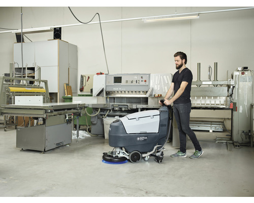 Mann bedient eine Nilfisk SC351 Scheuersaugmaschine in einer Werkstatt.