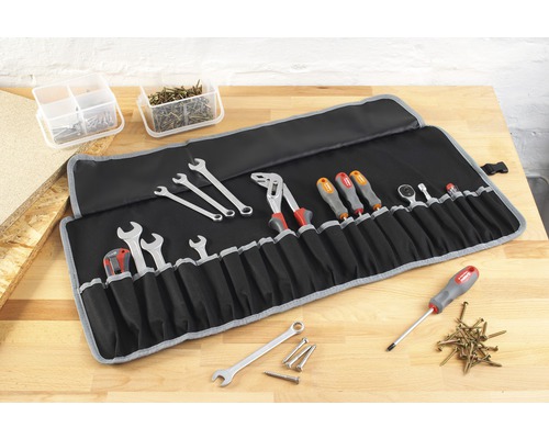 Werkzeugrollentasche mit Schraubenschlüsseln, Schraubendrehern, Zange und weiterem Werkzeug auf einer Werkbank