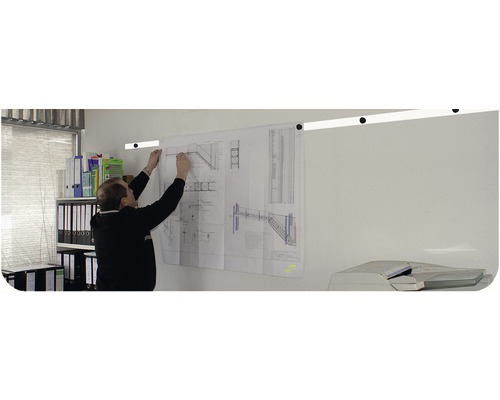 Mann befestigt Bauplan mit Treppenmotiven an einer Wandschiene in einem Büro.