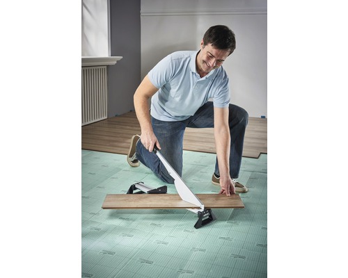 Ein Mann schneidet mit einem Laminatschneider eine Laminatdiele.