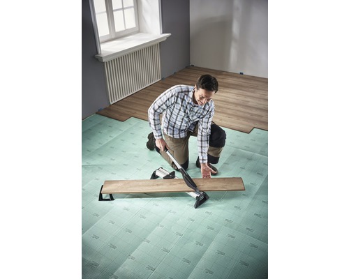 Mann verlegt Laminat mit Laminatschneider auf Trittschalldämmung