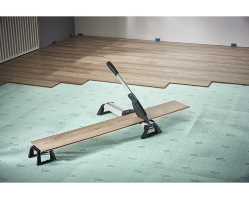 Laminatschneider beim Zuschneiden von Laminat auf einer Dämmatte