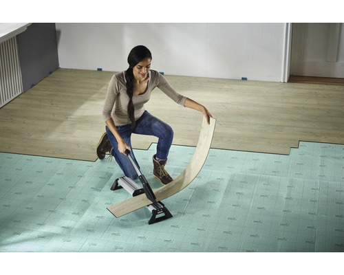 Frau schneidet Laminat mit einem Laminatschneider auf einem Unterlagsboden