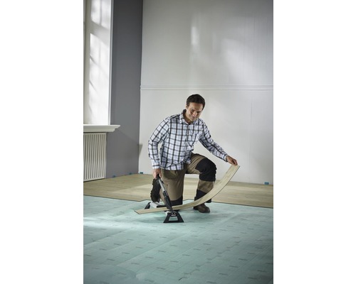 Mann verlegt Laminat mit Laminatschneider in einem Raum.