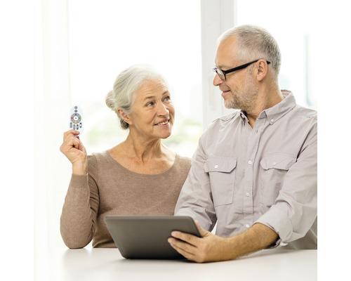 Älteres Paar bedient einen Tabletcomputer mit einer Fernbedienung.