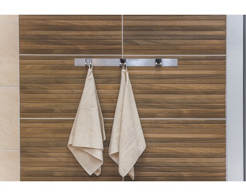 Badezimmeransicht mit Handtüchern an einem Handtuchhalter vor einer Wand mit Holzfliesen